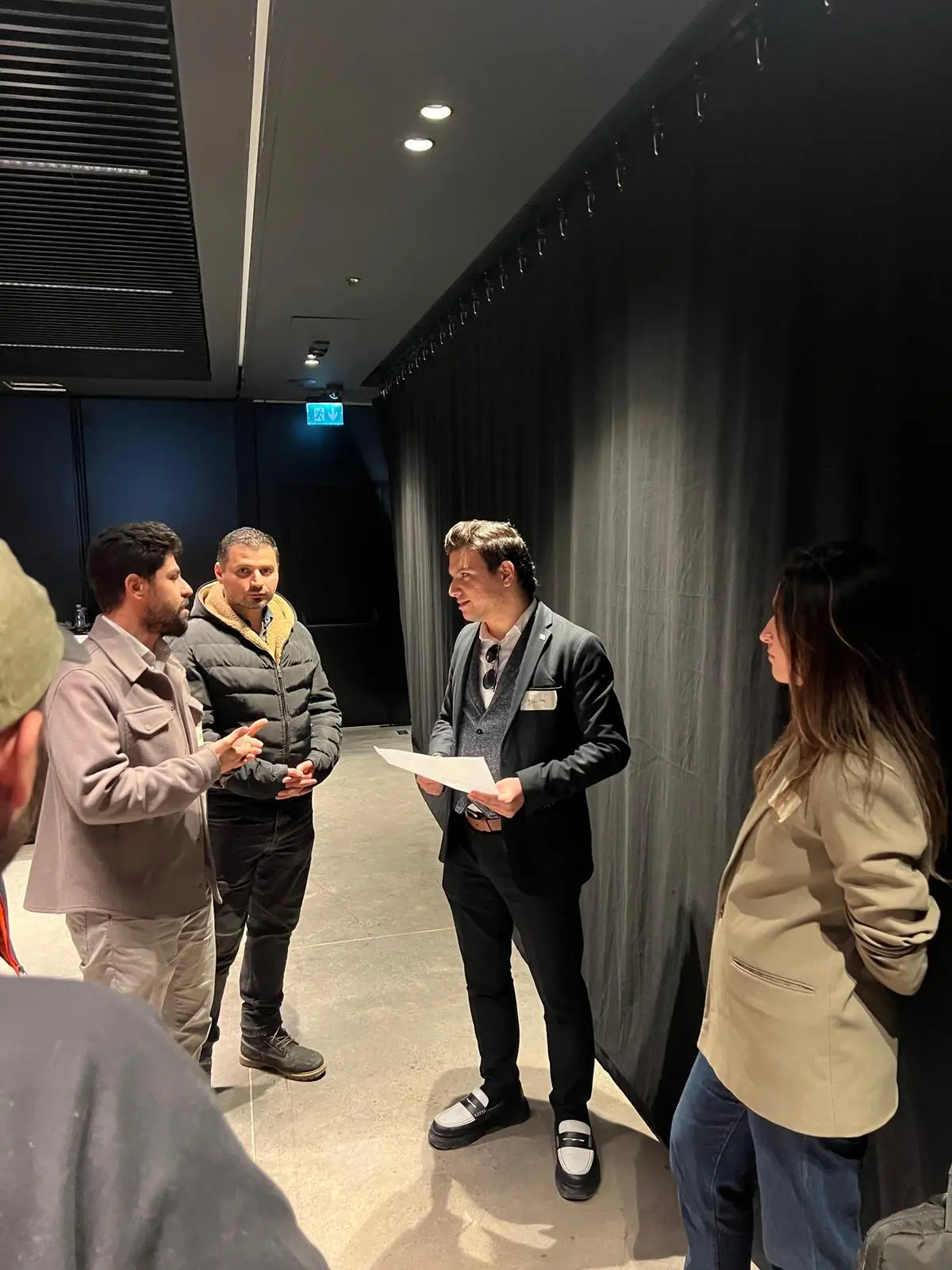 Kantesti компаниясының бас директоры Джулиан Эмир көк пиджак киіп, Түркиядағы 2025 жылғы Стамбұлдағы Клод саммитінде жасанды интеллект денсаулық сақтау саласындағы дизайн бойынша презентациясынан кейін бизнес мамандарымен және әзірлеушілермен байланыс орнатып, презентация жазып отыр.